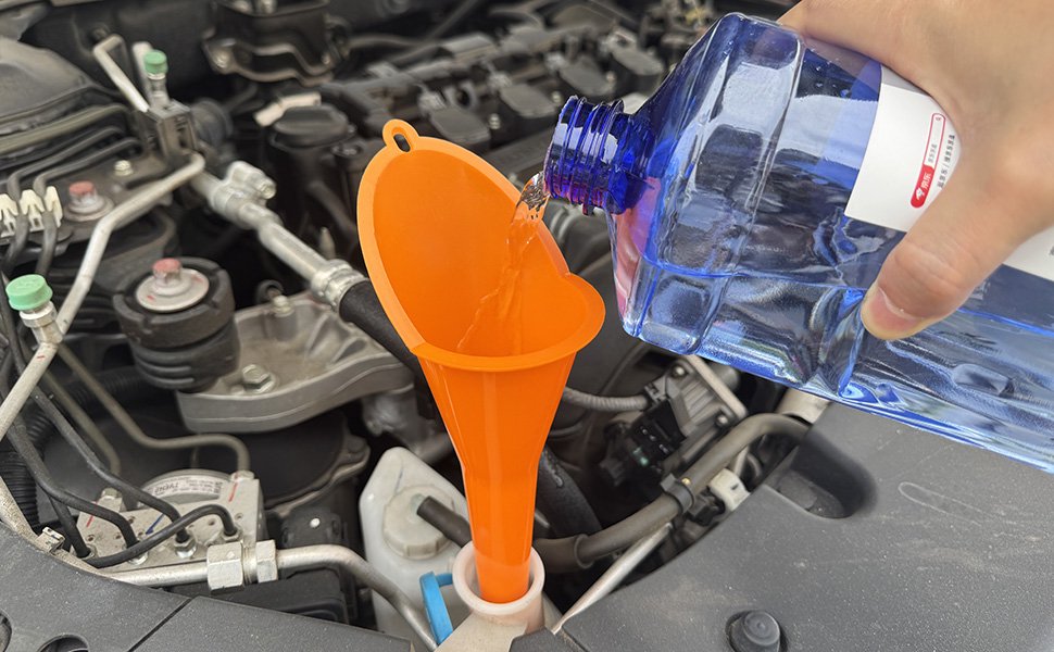Pouring windshield washer fluid from a blue plastic bottle into a car reservoir using an orange plastic funnel under the hood.